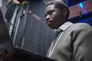 Bir sunucu odasında özenle çalışan yetenekli teknisyen, ağ istikrarı ve güvenliğini sağlayan ekrandaki sistem verilerini analiz ediyor.