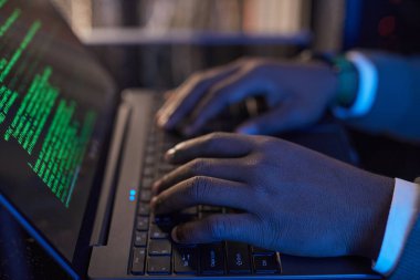 Ekranda yeşil metin olan dizüstü bilgisayarda yazma kodu, kol saati takmak, karanlık çalışma alanında doğal ışık kullanmadan programlama ortamı yaratmak