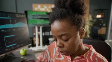 Modern iyi donanımlı programcılar ofisinde bilgisayar üzerinde çalışırken ekrana bakan konsantre siyah kadın bilişim uzmanının POV görüntüsü