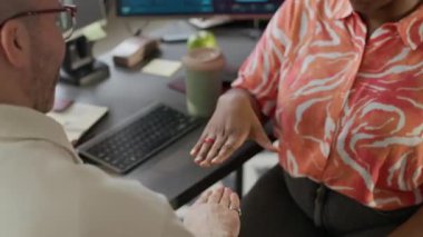 Açık uzay ofisindeki bir masada oturup taş kağıt makas oynayan, tanınmayan çok ırklı erkek ve kadın ofis çalışanları.