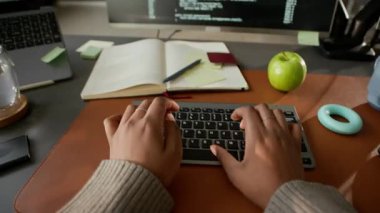 Bilgisayarda program kodu ve ofis masasında PC ile çalışırken tanımlanamayan yazılım mühendisinin POV görüntüsü
