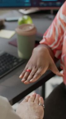 Açık uzay ofisindeki bir masada oturup taş kağıt makas oynayan çok ırklı erkek ve kadın ofis çalışanlarının dikey kesilmiş görüntüleri.