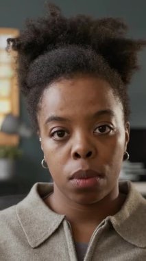 Dikey görüntü, odaklanmış genç siyahi kadın programcının modern ofiste çalışan ve arka planda program kodlarıyla çalışan bilgisayar ekranına baktığı görüntüler.