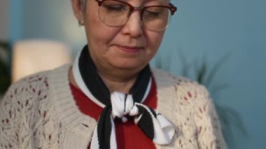 Gözlüklü, sıcak kahverengi giysili, ağırbaşlı, sakin, huzur dolu bir huzurevinde yaşayan yaşlı Asyalı kadının yavaş çekimini azalt.