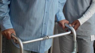 Yaşlılar için yaşam alanı olarak Walker 'ı kullanan yaşlı bir kadını destekleyen tanınmayan bakıcının orta kısmı.