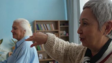 Huzurevindeki iki yaşlı kadının eğlenceli, keyifli, neşeli, güneşli oturma odasında eğlenirken gülüp dans ettiği belden aşağı vuruşlar.