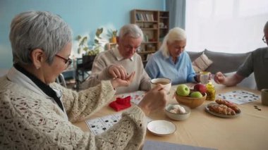 Neşeli bir grup yaşlı arkadaş çay, hamur işi ve meyvelerle tombala oynamak için toplanıyor. Parlak huzurevinde sıcaklık, kahkaha ve arkadaşlıkla dolu.