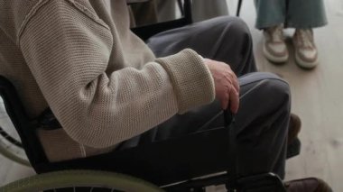 Terapi seansında yaşlı bir adamın nazikçe elini tutan tanınamayan terapistin yakın çekimi. Bakımı, empatiyi ve insan ilişkilerini sembolize ediyor.