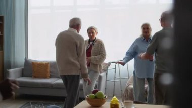 Yaşlılardan oluşan bir grup, genç bakıcılarıyla neşeyle dans ediyor, neşe dolu bir huzurevinde, neşe, hareket ve duygusal bağlantıyı destekliyor.