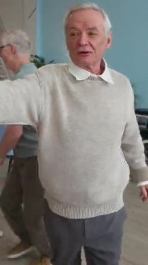 Huzurevinde rahat bir huzur evinde dans eden, birlikte eğlenen ve mutlu anları paylaşan dört son sınıf öğrencisinin dikey çekimi.