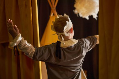 Peri masalı sırasında çocuk tiyatrosunda sahne alırken, üzerinde kağıt taç olan kral kostümü giymiş küçük bir çocuğun sahne alması.