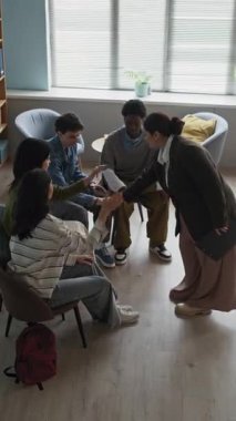 Genç melez kadın öğretmenin dikey yavaşlaması çeşitli gençlerle el ele oturması pozitif ilişkiyi, karşılıklı desteği ve sınıfta işbirliğini teşvik ediyor.