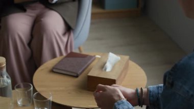 Tanımlanamayan bir hastanın önünde oturan, elleri çapraz oturan ve rahat ofisinde bireysel terapi seansında sorular soran melez genç kadın danışmanın yavaşlığı.