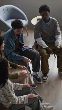 Çok ırklı gençlerle el ele tutuşup motivasyon ve takım ruhunu cesaretlendiren kadın öğretmenlere ilham veren dikey yüksek açı çekimi.