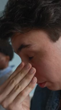 Hayal kırıklığına uğramış Kafkasyalı gencin dikey yakın çekimi. Sınıfta çeşitli akranları arasında oturuyor ve gözlerini ve yüzünü düşüncelerinin derinliklerine sürtüyor.