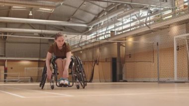 Spor salonundaki antrenmandan önce tekerlekli sandalyedeki beyaz kızın ısınma hareketleri.
