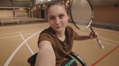 Elinde badminton raketi tutan, konuşan, gülümseyen ve iç sahada kameraya bakan 15 yaşında beyaz bir kızın el bilgisayarı.