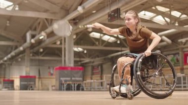Sarışın, beyaz, tekerlekli sandalyede badminton oynayan, iç sahada raketle servis yapan beyaz kız.