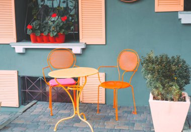 Sarı masalı ve renkli sandalyeli sokak kafesi. Renk tasarımı, yaratıcı kopya alanı 