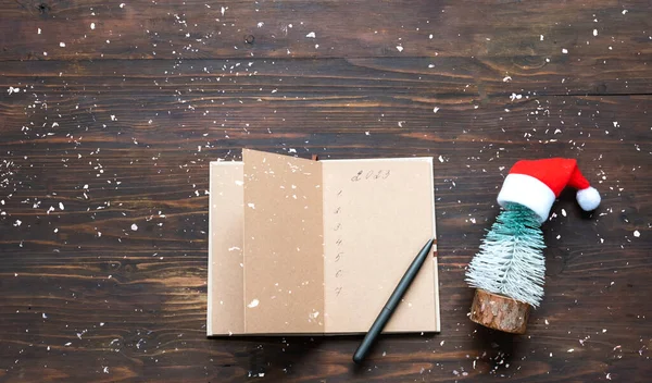 Goals in notebook for 2023 on wooden background with sparkles . Festive concept. Atmospheric mood in trendy colors of the New Year.