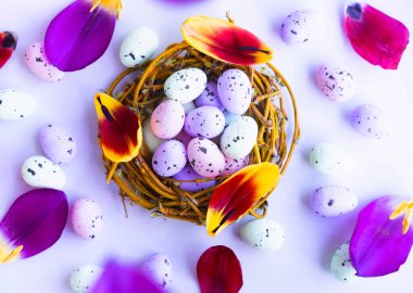 Mor arka planda çiçek yapraklarıyla Paskalya yumurtaları havada uçuşuyor. Mutlu Paskalyalar. 