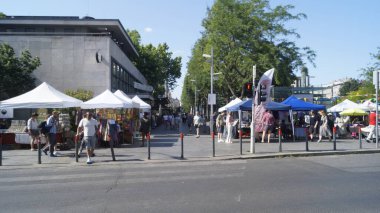  People browse and walk among stalls at a lively outdoor street market. 2025