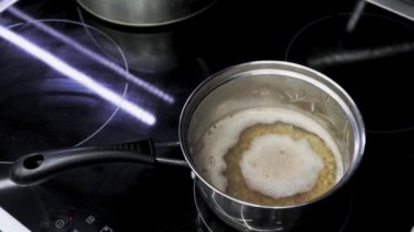 Buckwheat porridge is cooked in metal saucepan. Kitchen cooking food on induction cooker