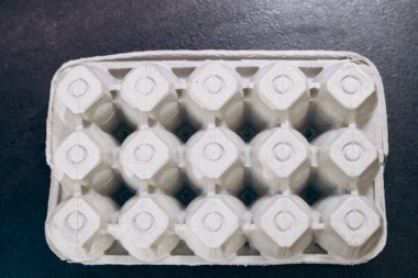 Paper cardboard box egg tray lies on table with demanding white eggs