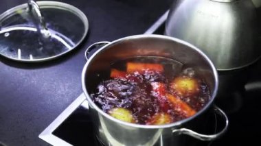 Water boils in steel pot and vegetables are boiled for salad