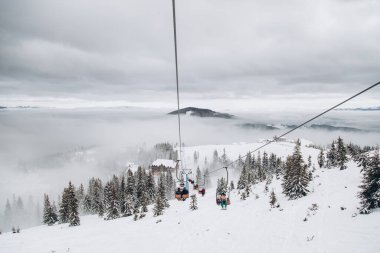 20.01.23 Dragobrat, Ukraine snowboarder rides ski lift in snow-covered mountains of Carpathians