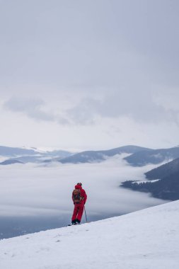 Skier rides high in snow in mountains. Fog on mountain and people skiing
