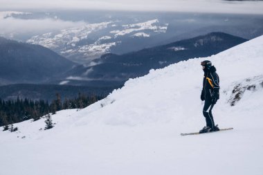 Skier rides high in snow in mountains. Fog on mountain and people skiing