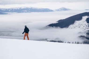 Skier rides high in snow in mountains. Fog on mountain and people skiing