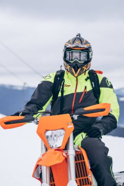 Two snowboarders sit on moto snowmobile on snow high in mountains