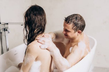 Guy and girl bathe in bathroom together and smear each other with foam
