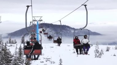 20.01.23 Dragobrat, Ukraine snowboarders rides ski lift in snow-covered mountains of Carpathians