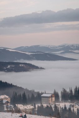 Dragobrat, Ukraine mountain landscape with fog and fir trees. Dawn in a snowy ski resort