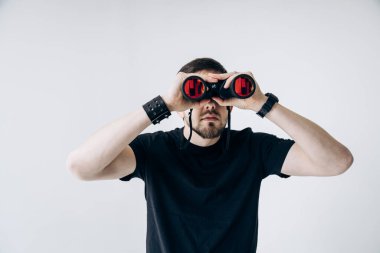 Siyah tişörtlü adam dürbünü tutuyor ve içine bakıyor.