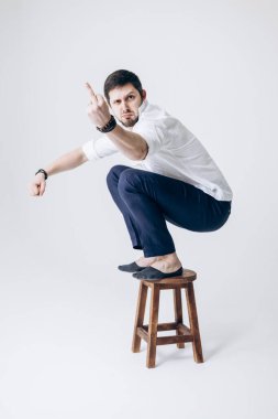 Beyaz gömlekli, sakallı yakışıklı bir adam portresi sandalyede oturuyor.