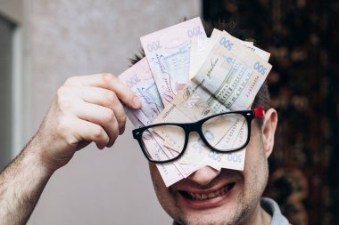 Gözlüklü ve içinde Ukrayna parası olan bir adam. Başla. Yeni iş, bir milyon dolarlık parlak fikir. Büyük banknotlar halinde Hryvnia