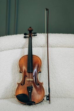 Tahta kahverengi keman beyaz kanepede yatıyor. Kemancı için müzik aleti