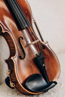 Tahta kahverengi keman beyaz kanepede yatıyor. Kemancı için müzik aleti