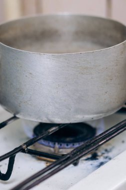 Metal tencere yavaş ateşte ısıtılır. Gaz ocağında yemek pişirmek.
