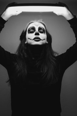 Cadılar Bayramı makyajlı kız lambayı kendinden yukarıda tutuyor.