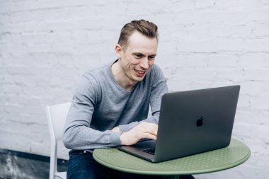 Gri ceketli adam, bilişim uzmanı, dizüstü bilgisayarda oturuyor ve çalışıyor.