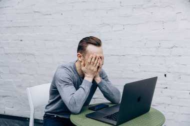 Gri ceketli adam, bilişim uzmanı, dizüstü bilgisayarda oturuyor ve çalışıyor.