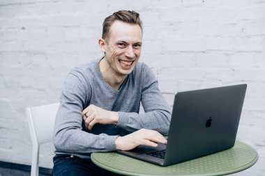 Gri ceketli adam, bilişim uzmanı, dizüstü bilgisayarda oturuyor ve çalışıyor.