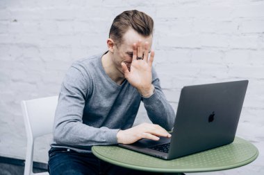 Gri ceketli adam, bilişim uzmanı, dizüstü bilgisayarda oturuyor ve çalışıyor.