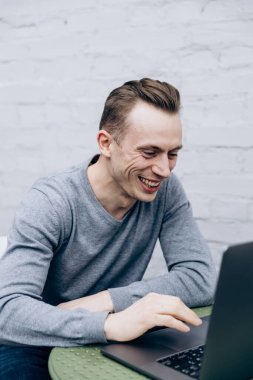 Gri ceketli adam, bilişim uzmanı, dizüstü bilgisayarda oturuyor ve çalışıyor.