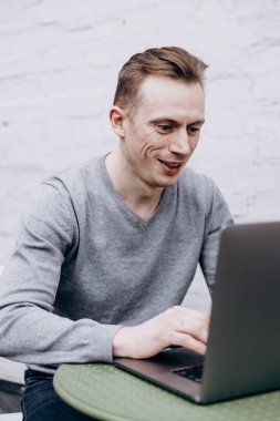 Gri ceketli adam, bilişim uzmanı, dizüstü bilgisayarda oturuyor ve çalışıyor.